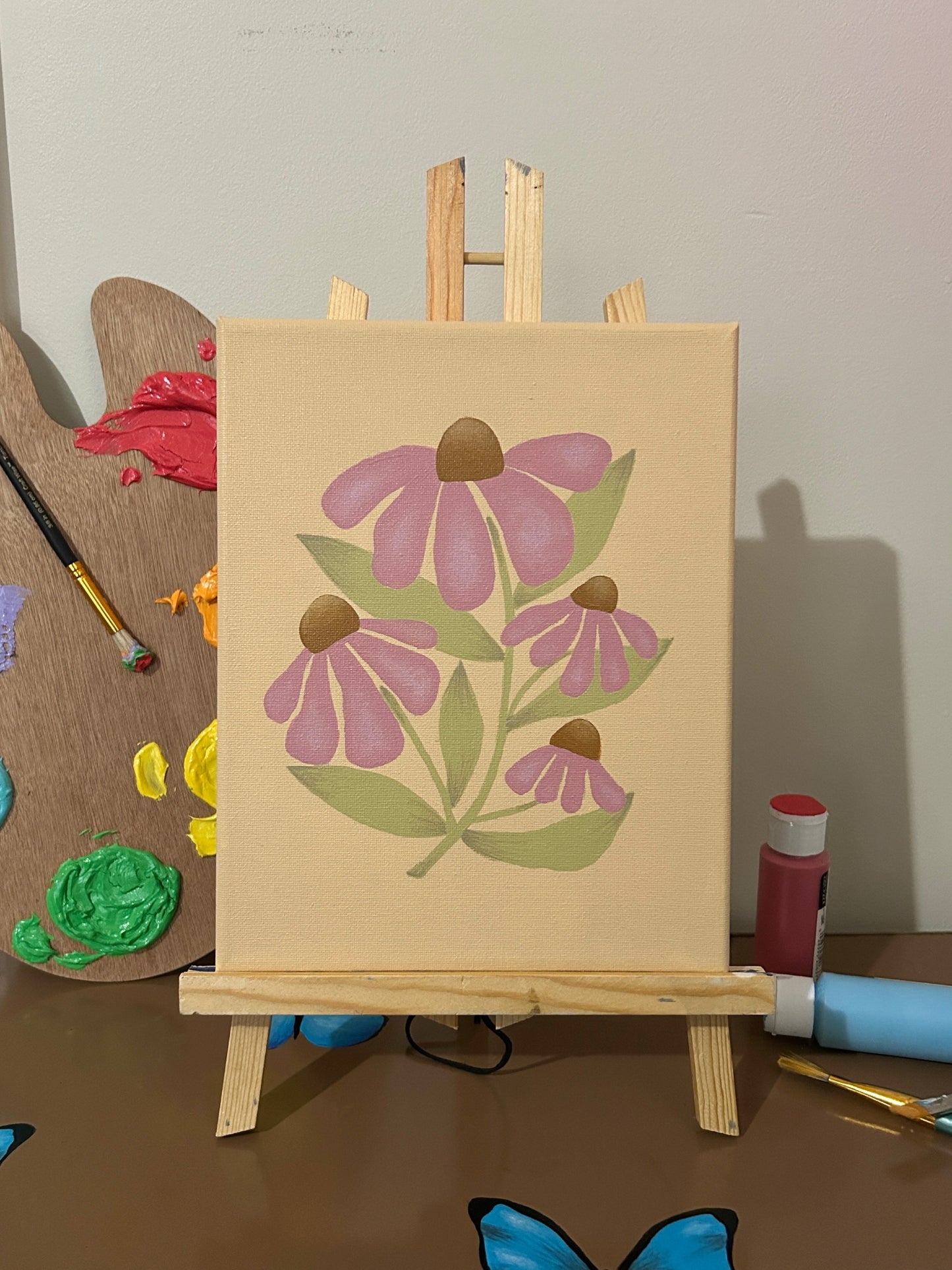 Amber Peeks Art: Painting of purple flowers on a wooden easel with art supplies in the background.