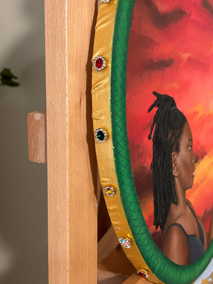 Amber Peeks Art: Decorative painting with gold frame and gemstones, featuring a woman against a sunset background.