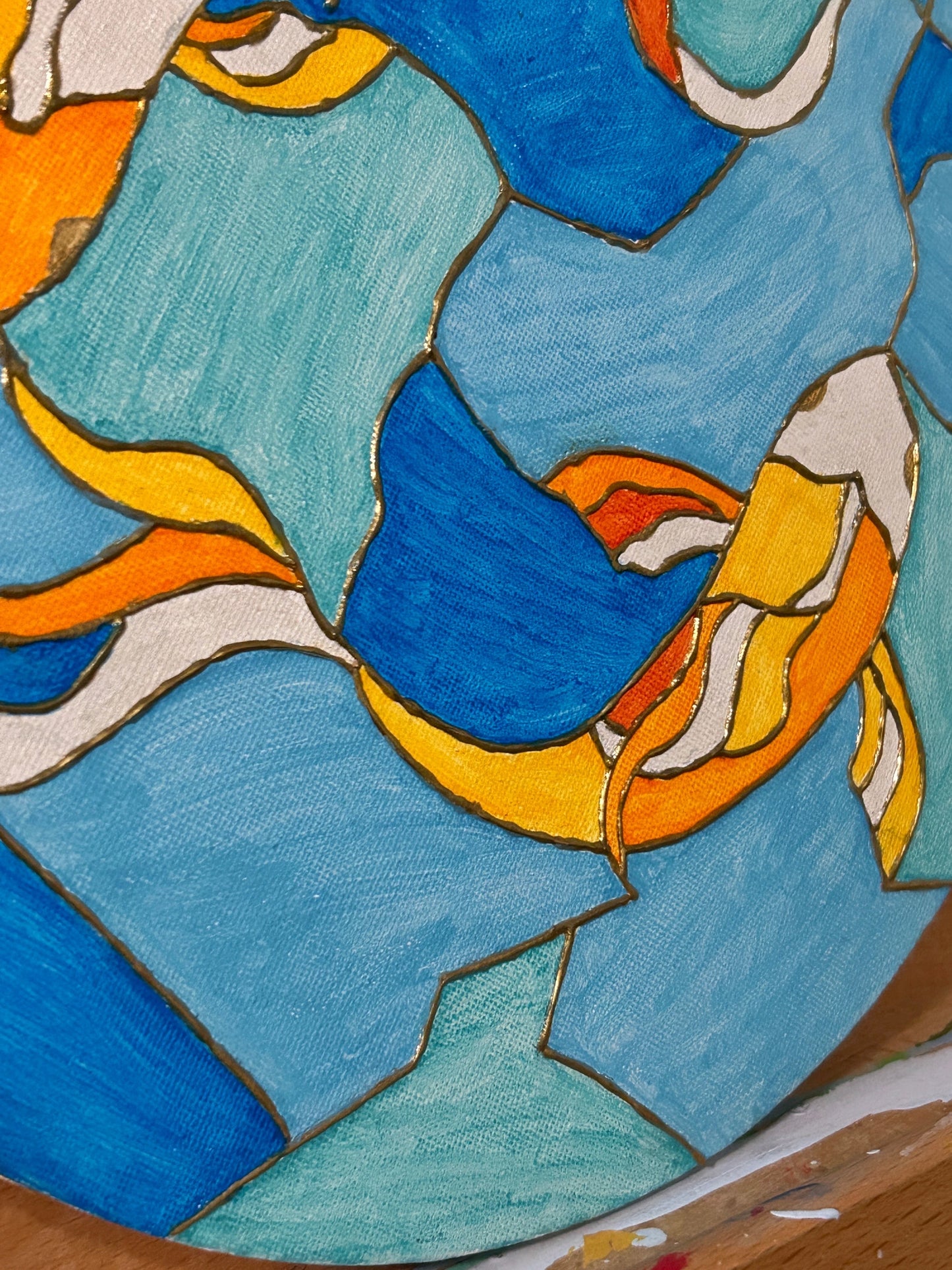Amber Peeks Art: Wooden art easel with a round paint palette featuring colorful fish designs on a blue background.