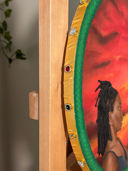 Amber Peeks Art: Decorative painting with gold frame and gemstones, featuring a woman against a sunset background.