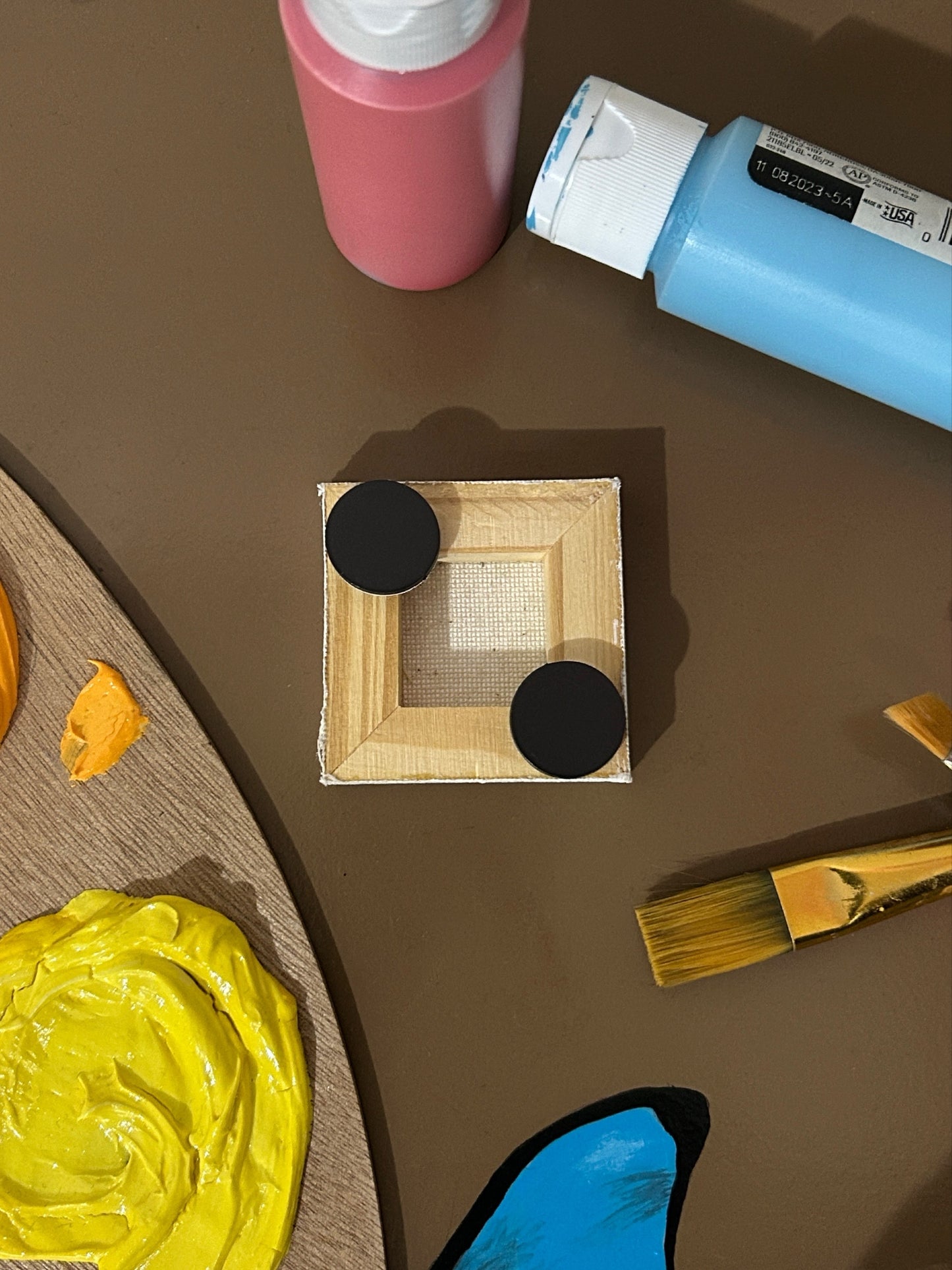 Amber Peeks Art: Small white ghost magnet on a dark surface with pumpkins, sunflowers, and a paint palette.