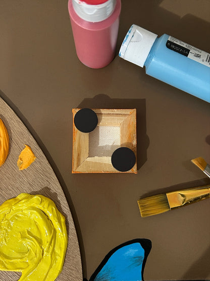 Amber Peeks Art: Small orange magnet with a pumpkin face design on a brown surface with art supplies.