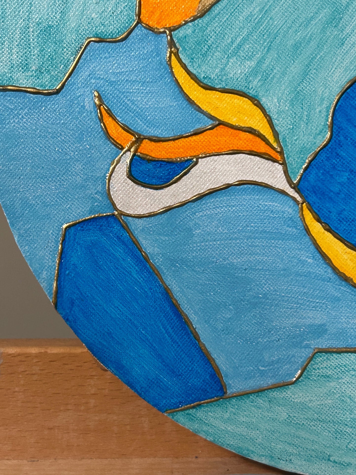 Amber Peeks Art: Wooden art easel with a round paint palette featuring colorful fish designs on a blue background.
